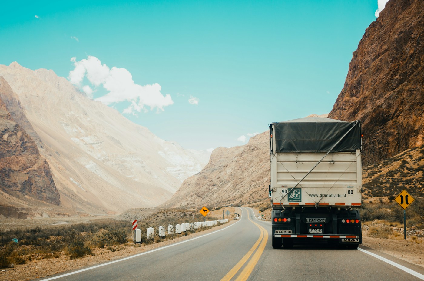 Rear of a cargo truck on a winding road through dry mountains